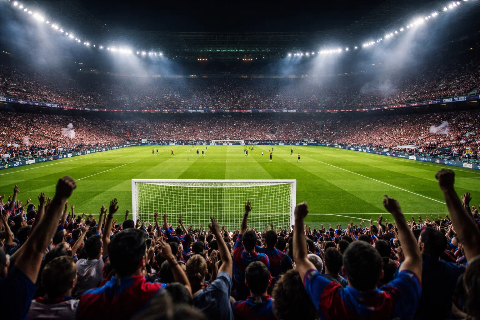 Stadio di calcio illuminato durante una partita serale con atmosfera elettrizzante