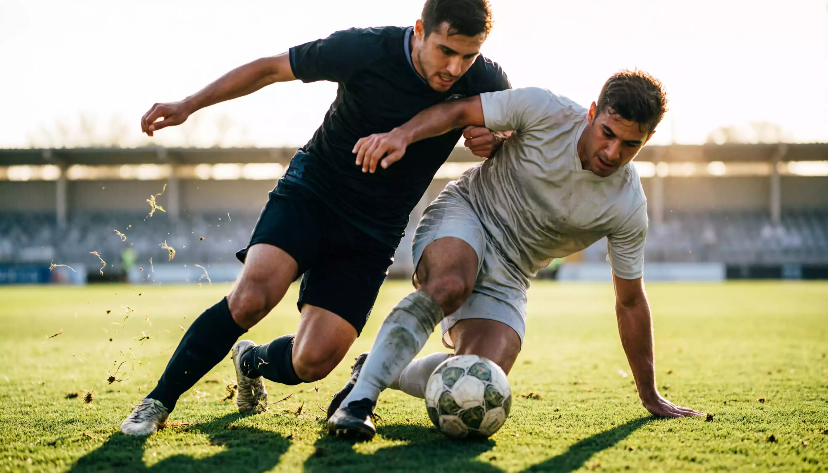 Due giocatori di calcio in contrasto durante un'azione di gioco su un campo in erba